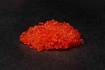 Red trout caviar on a black background.