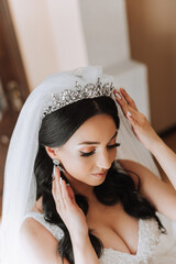 Fototapeta premium Portrait of the bride in the hotel room. A beautiful young girl is dressed in a white wedding dress. Modern wedding hairstyle. Natural makeup.
