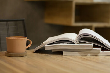 Close up stack of magazine or books with cup of coffee on wooden table in copy space concept.
