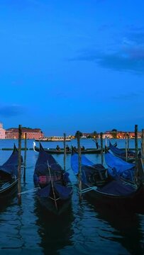 Romantic vacation Venice travel background - gondolas in lagoon of Venice by Saint Mark (San Marco) square with San Giorgio di Maggiore church in background in the evening in Venice, Italy. Camera pan