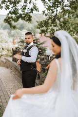 The bride is dressed in an elegant lush white wedding dress with a long veil and is ready for her groom. The first meeting of the bride and groom