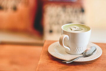  Close up and selective focus cup of hot matcha latte art on wooden table.