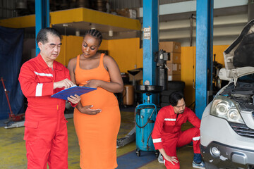 Car mechanic service and maintenance car engine concept. Male mechanic and female car owner customer discuss and checking car engine together in auto repair shop