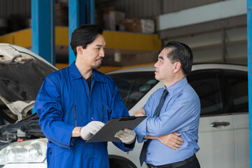 Car mechanic service and maintenance car engine concept. Male mechanic and senior male car owner customer discuss and checking car engine together during repair process in auto repair shop