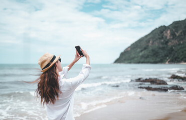 Fototapeta na wymiar beach, sand, relax, sea, summer, vacation, girl, holiday, tropical, female. young woman taking selfie by smartphone on the beach with sunny day and smiling with a blue sky. Travel and lifestyle summer