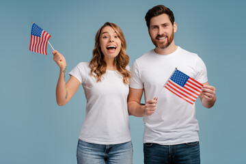 Overjoyed man and woman holding American flags isolated on blue background. Voting, Election day...