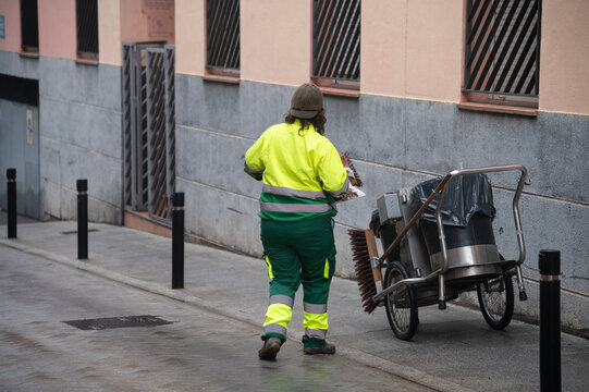Una operaria municipal de limpieza con su escoba y recogedor limpia en una calle de una ciudad espa&ntilde;ola.