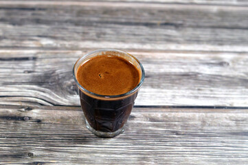 A glass cup of Turkish coffee made of coffee beans, seeds of the Coffea plant and the source for...
