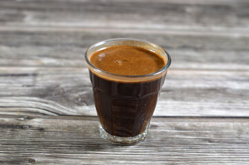 A glass cup of Turkish coffee made of coffee beans, seeds of the Coffea plant and the source for...