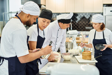 multicultural chefs in blue aprons and toques working hard on their pastry together, confectionery - obrazy, fototapety, plakaty