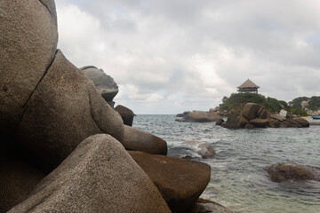 Shore rocks in middle of caribbean sea with hut viewpoint at cabo san juan beach into tayrona park