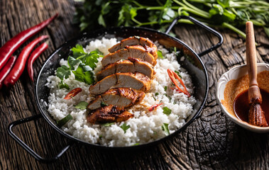 Grilled chicken breast served in a pan with jasmine rice and chili peppers
