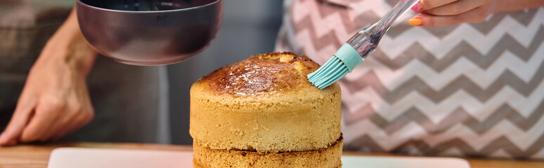 young woman with apron brushing cake with syrup on cake during cooking lesson, courses, banner