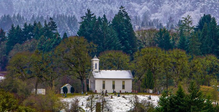 A country church with graveyard near Salem, Oregon.  A light snow covers the surrounding agricultural fields