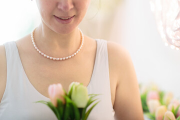 Jewelry gift. Pearl necklace on woman with flowers