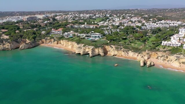 Aerial perspective of spectacular Algarve coastline. View of Armacao de Pera. Luxury hotels and urbanisation. Gloden beaches. High cliffs. Drone forwards. Travel destination in South of Portugal