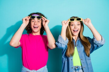 Portrait of young surprised funny couple hipsters touching sunglasses at summer hipster party...