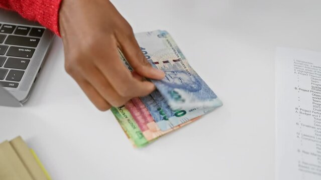 African woman handles south african rand in modern office setting