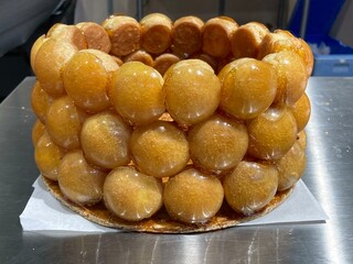 Pastry: making a cake with choux pastry dipped in caramel