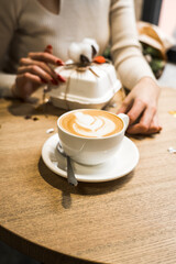 Happy woman drinking coffee and celebrating birthday in coffee shop with bouquet of tulips and bento cake.Birthday concept.Bento cake gift