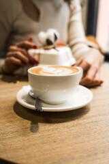 Happy woman drinking coffee and celebrating birthday in coffee shop with bouquet of tulips and bento cake.Birthday concept.Bento cake gift