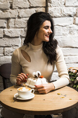 Happy woman drinking coffee and celebrating birthday in coffee shop with bouquet of tulips and bento cake.Birthday concept.Bento cake gift