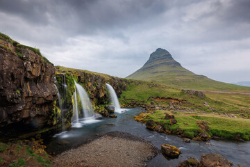 Summer landscape of Nordic nature, coastal hinterland in Iceland with picturesque valley and magnificent Kirkjufell mountain in the background