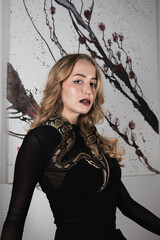 young blond woman with black dress and real snake python 