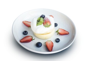 Close-up, Japanese-style pancake topped with mixed fruits, strawberries, kiwi, and blueberries on the top of a cake placed isolated on white background.
