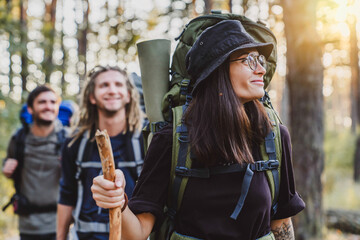 Group of friends trekking while traveling with backpacks walking in forest. Male and female tourists doing track on mountains together. Adventurers explorers in woods