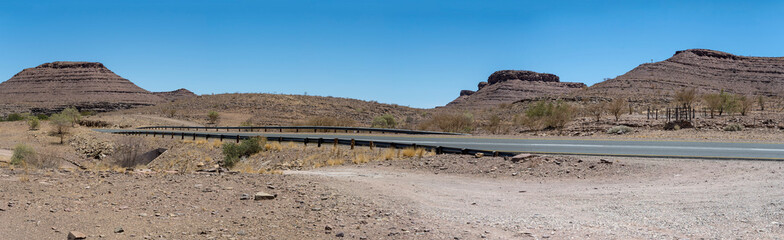 B4 tar road and hills with layers of conglomerate and basalt in desert , near Fort Naiams,  Namibia