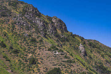 Rocky mountains with green grass under a blue sky in summer
