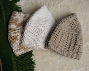 Collection of songkok hats, decorative Islamic headdresses worn by Muslim men, isolated on white fur carpet background from different angles. Songkok is made from hand-knotted thread ramadhan eid fitr