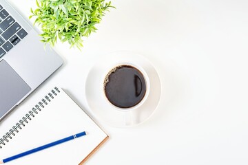 coffee cup, notebook, laptop on a white table in the office. Working concept using technology,...