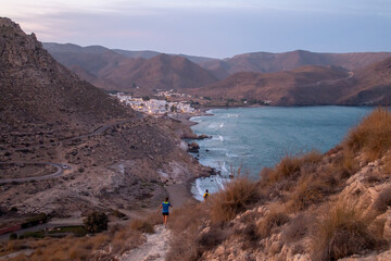 Sendero de La Molata en Las Negras, Andalucía, España. Pareja de senderistas caminando hacia el norte en dirección al pueblo en la bahía de Las Negras al atardecer.