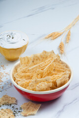 Red enameled bowl filled with tarhana chips, Turkish snack made with flour, wheat berries, mint, yogurt and spices also known as frik