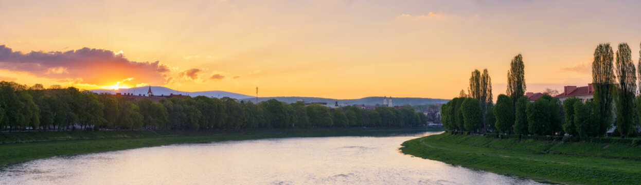 gorgeous sunrise on the river uzh of ukraine. beautiful urban scenery of uzhgorod downtown in spring. cityscape with grassy embankments of the longest linden alley in europe and kyiv chestnut alley
