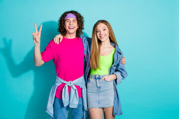 Portrait of two best friends youngster curly hair guy and blonde lady show v sign victory symbol isolated on aquamarine color background