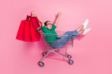 Full body photo of optimistic funny woman sit in shopping cart look empty space raising up new...