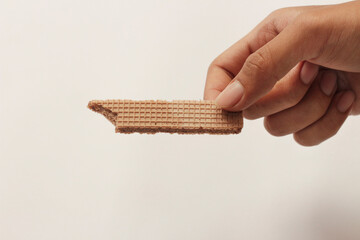 Wafers with chocolate flavored cream on a white and wooden background. Wafer With Chocolate Drizzle. A set of delicious crispy sweet wafers of different shapes. long, square, tasty and crunchy cake.