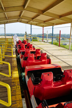 Empty Red Roller Coaster Cars At Rural Amusement Park, Eye-Level View