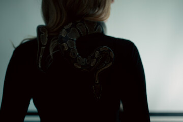 young blond woman with black dress and real snake python 