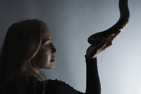 python snake plays with a young blond woman