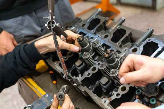 Auto mechanics assembling a disassembled car engine in a workshop