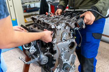 Auto mechanics assembling a disassembled car engine in a workshop