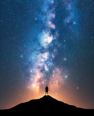 Milky Way and sporty man on mountain peak at starry night