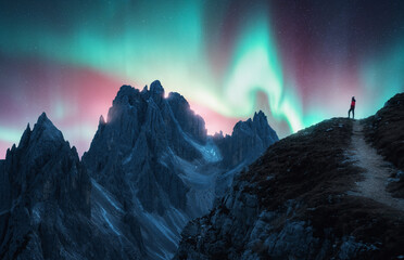 Northern lights and woman on mountain peak at starry night