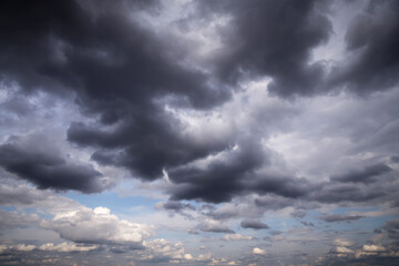 Storm dark grey and white cumulus rain clouds against blue sky background texture, thunderstorm