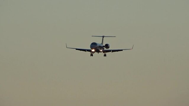 Black generic private jet flying final approach into airport at dusk golden hour evening
