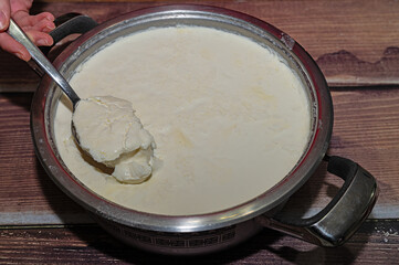Woman taking a spoonful of home-made yoghurt fermented in a pot.